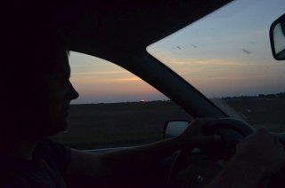 Юра ведёт машину на фоне рассвета.